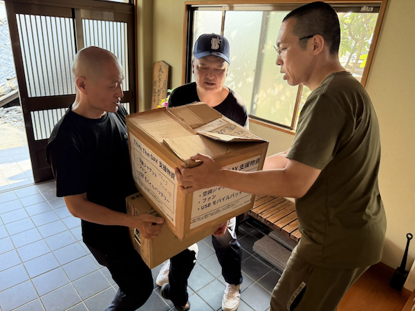 小山住職(右)に物資を届ける岩崎住職(左)と黒田住職=12日、浄土真宗本願寺派光圓寺