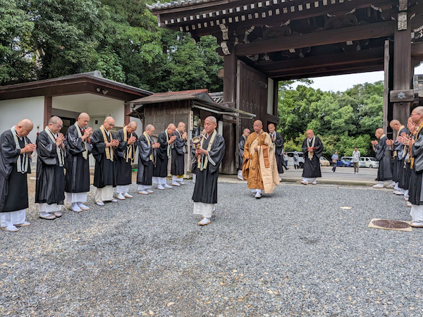 川村宗務総長ら内局と自坊関係者らに出迎えられ、山門を入る小林長老＝総本山泉涌寺
