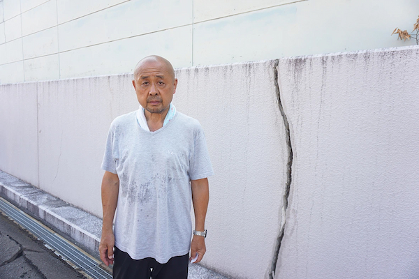「鉄骨で補強した塀もひび割れた」と語る稲田住職＝宇城市の不動明王寺
