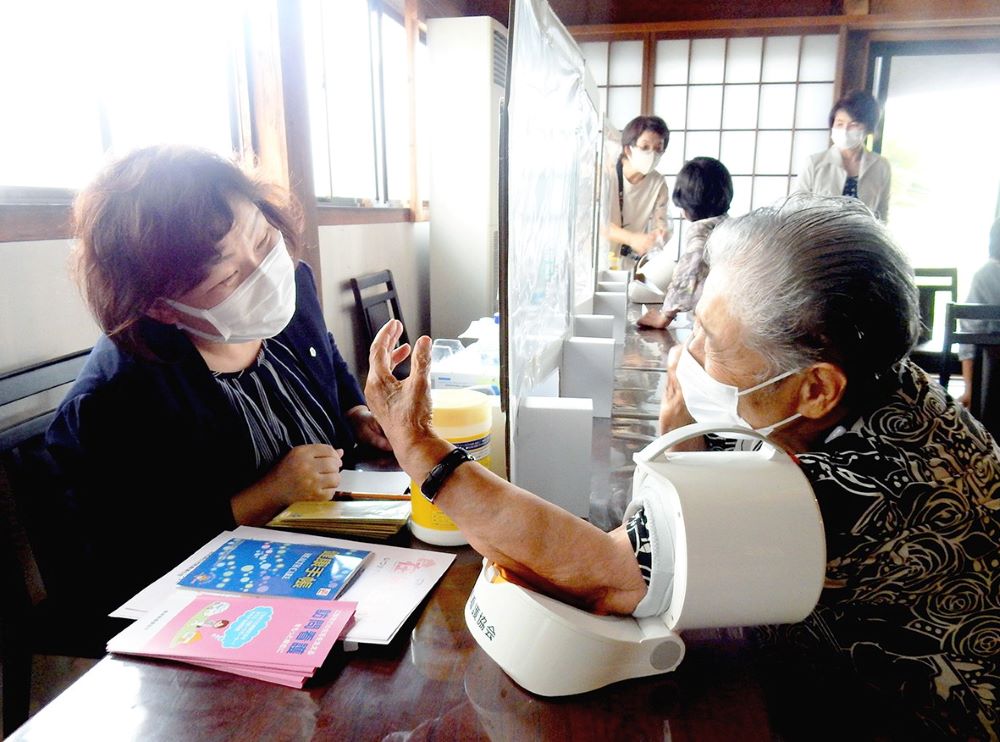 まちの保健室で看護師から血圧を測ってもらう女性（右）