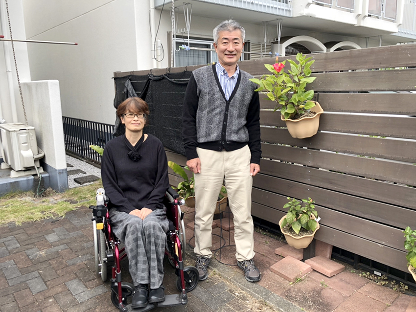 自宅の前で。堀さつきさん（左）と夫の充さん