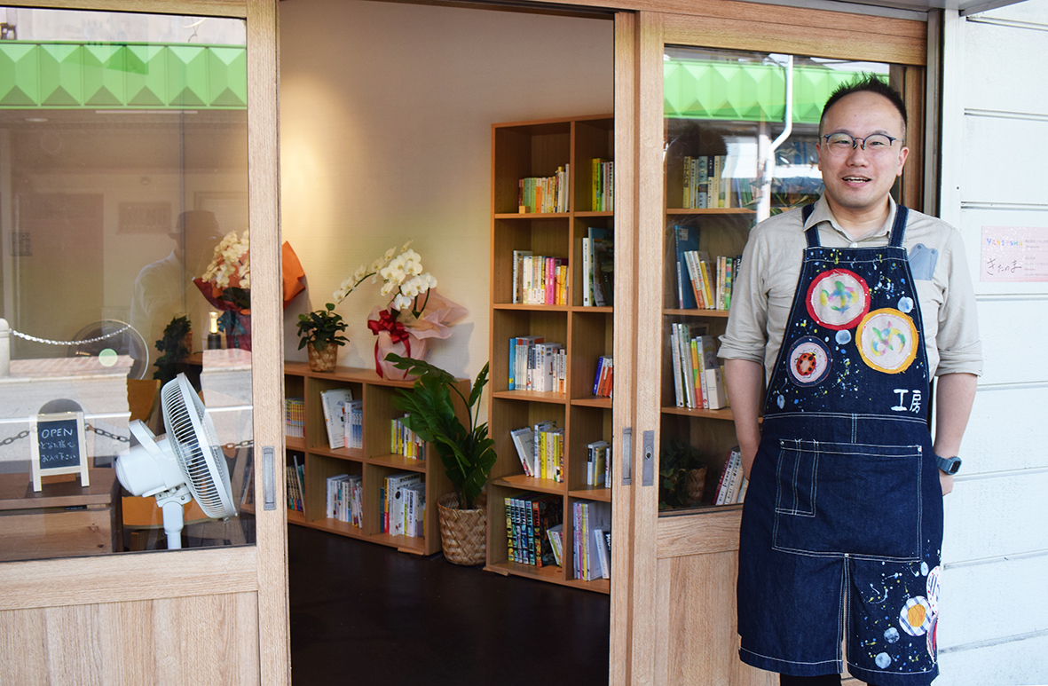 (画像02:商店街で開いたインクルーシブまちづくり図書館「きたのま」と新山さん)