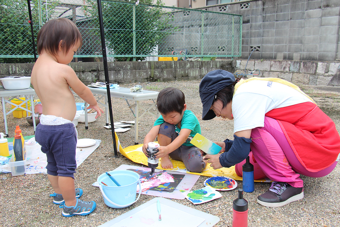 スタッフに見守られながら絵の具で戯れる子どもたち