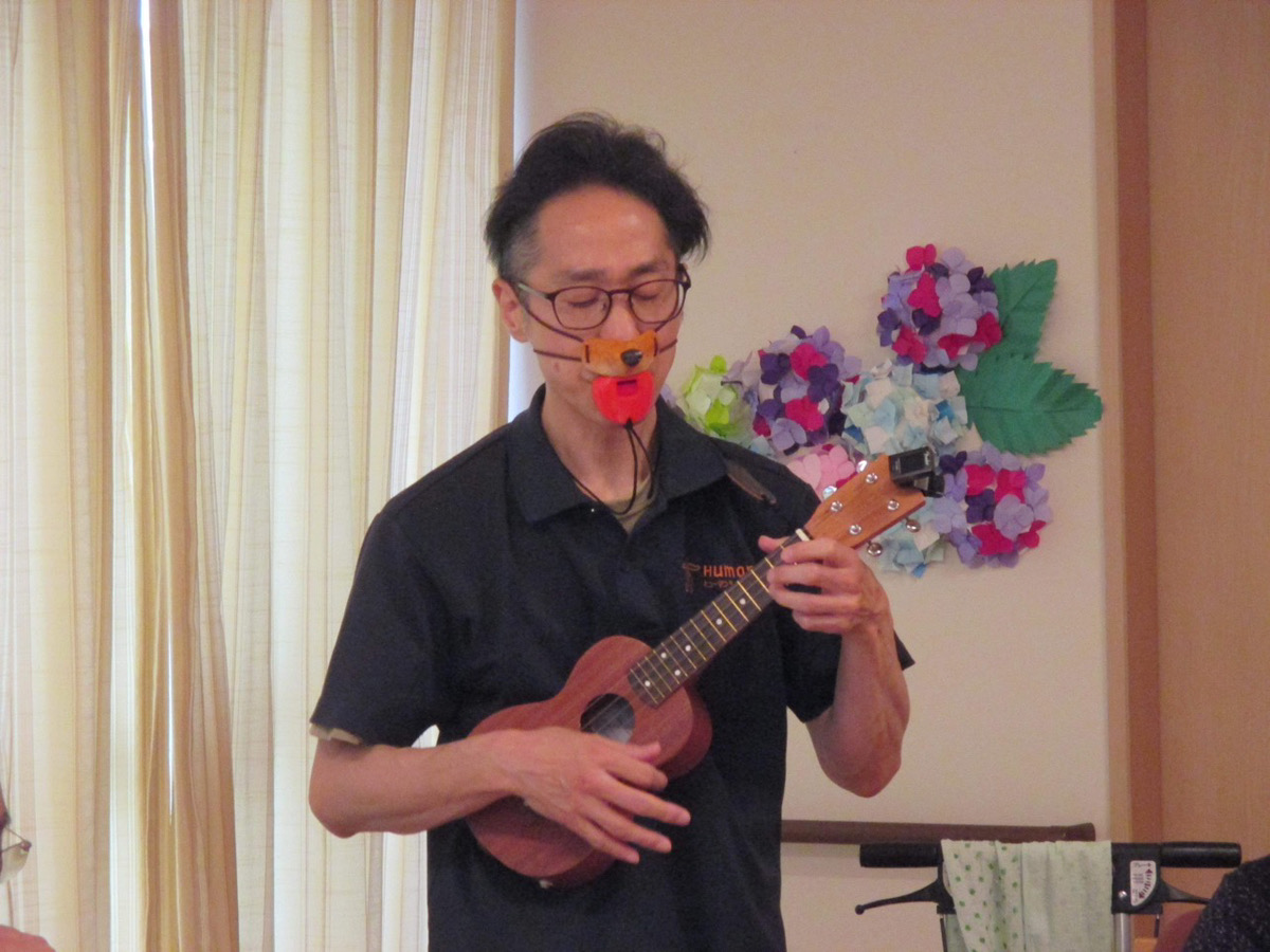 写真①　施設で演奏する田中さん
