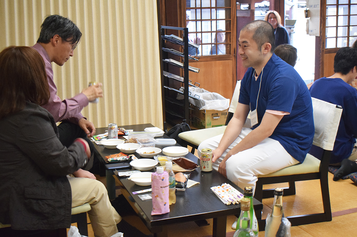 (画像①アイキャッチ兼用無職酒場:「無職酒場」で参加者と談笑する大植医師(右)=21日、幸教寺)