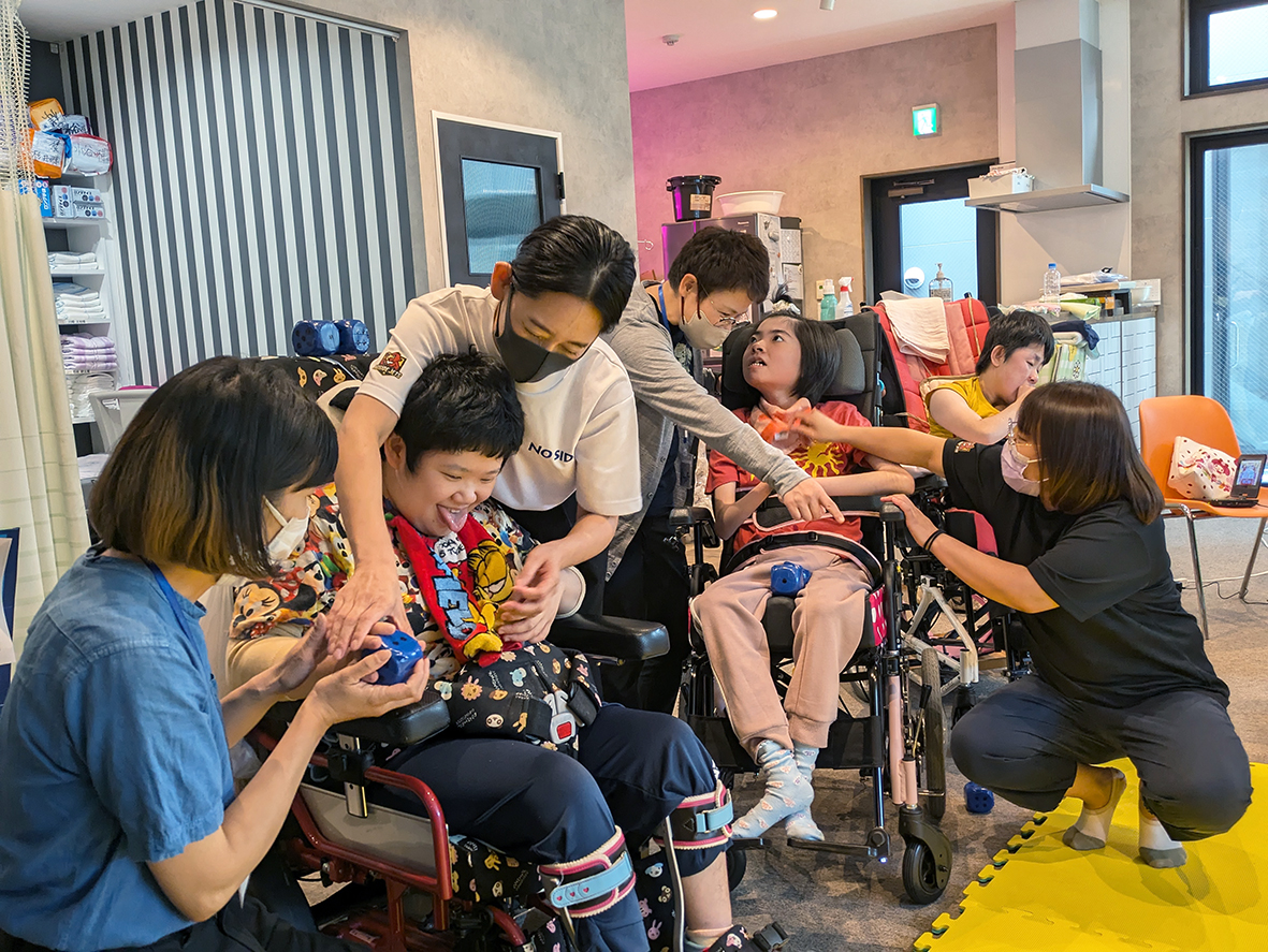 (画像①:佐藤歩実さんへの食事介助を見学する「ぷろちゃれ」の参加者たち)