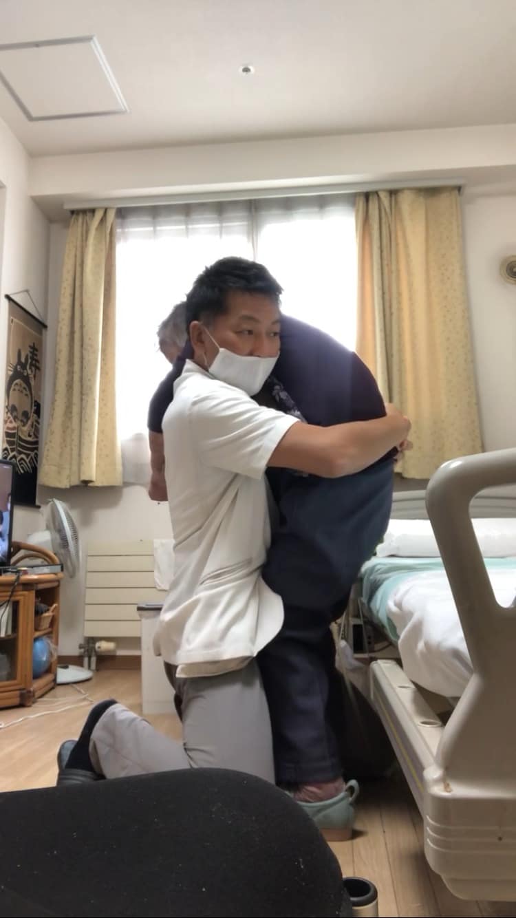 利用者と立ち上がりの訓練を行う佐藤健太郎さん