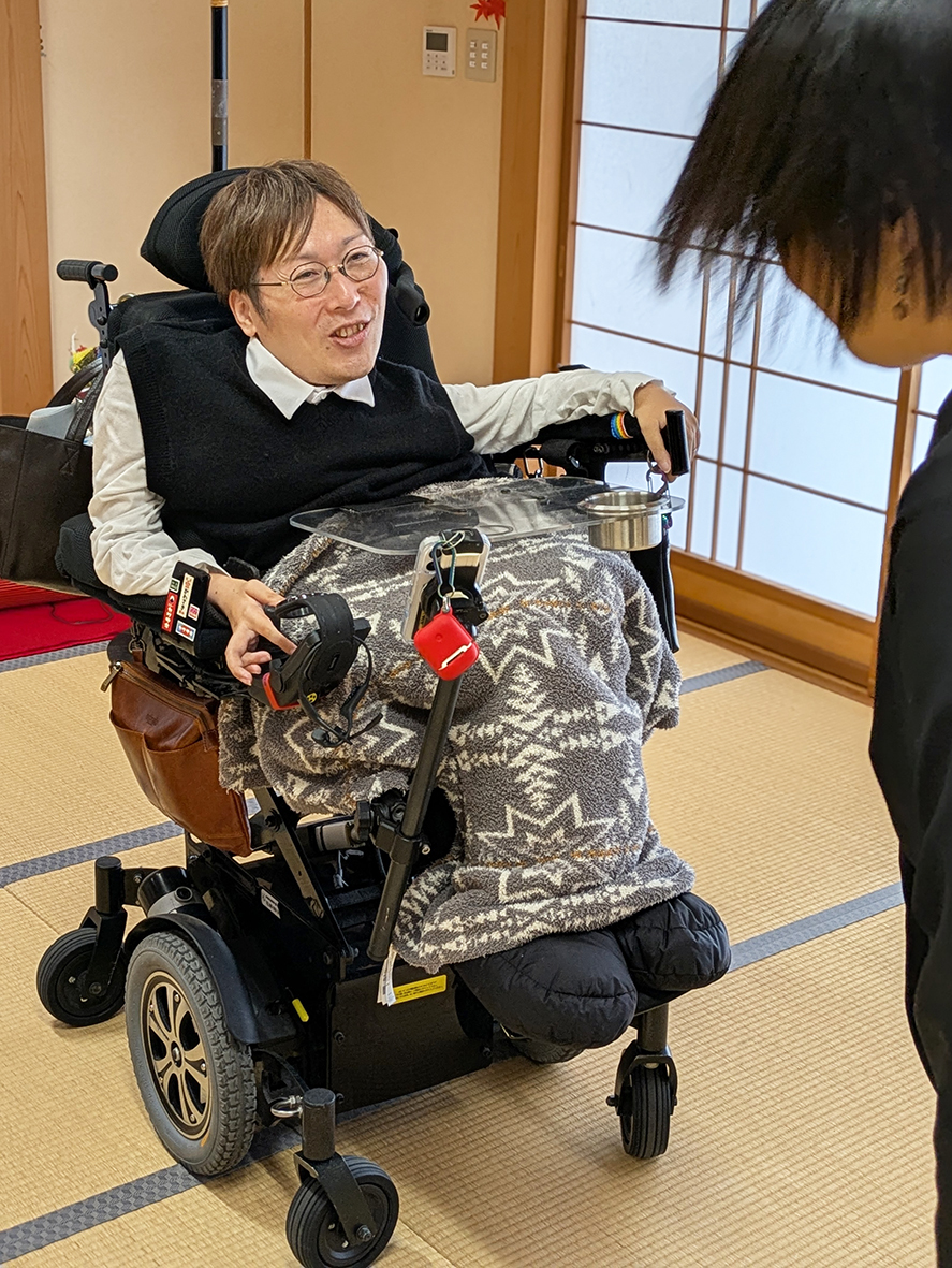 （画像１：語らいカフェのあと、参加者と談笑する川﨑さん＝鹿児島市）